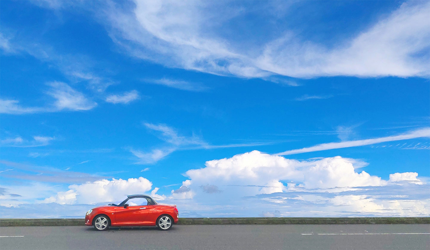 青空の下を走る赤い自動車