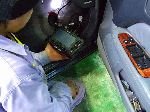 診断機を車両に接続して故障箇所を点検する整備士