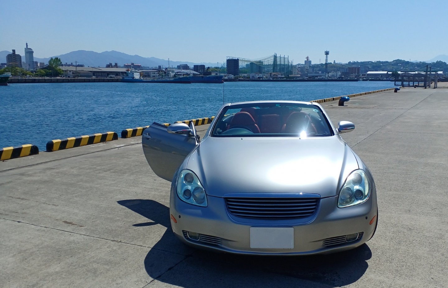 港に停車するシルバーのオープンカーの中古車イメージ